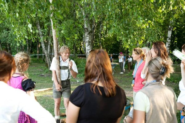 Ein Mann mit einem Baumstamm in der Hand, der die Team-Challenge erklärt